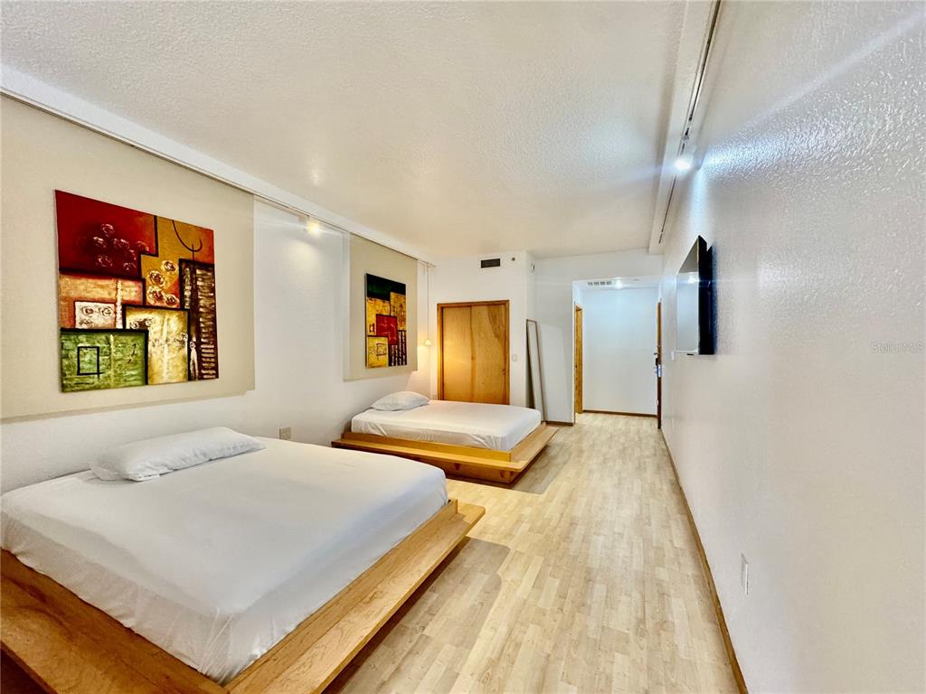A bedroom features two platform beds, light wood flooring, and abstract wall art — 101 PALM HARBOR PARKWAY UNIT B414, PALM COAST, FL