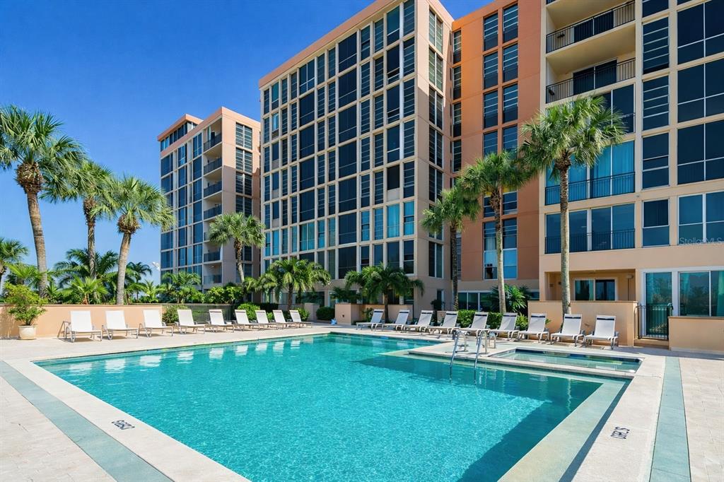 A swimming pool and hot tub sit in front of a multi-story apartment building — 7400 SUN ISLAND DRIVE S UNIT 103, SOUTH PASADENA, FL
