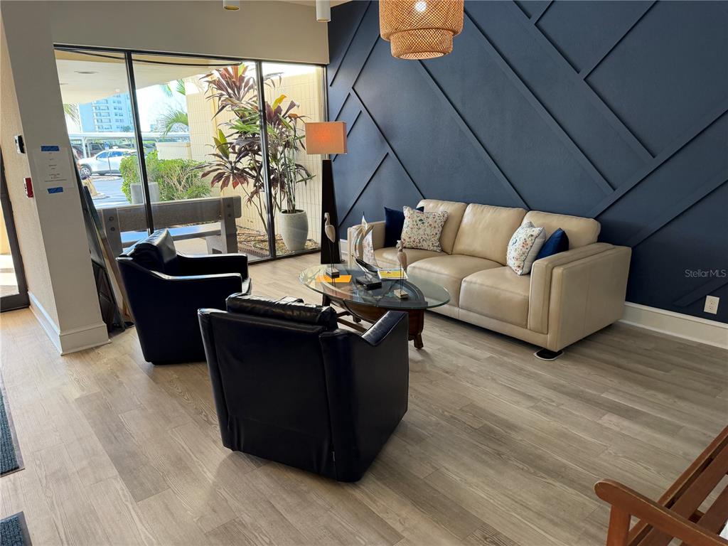 A seating area features a beige sofa, two black armchairs, and a dark blue accent wall — 7400 SUN ISLAND DRIVE S UNIT 103, SOUTH PASADENA, FL