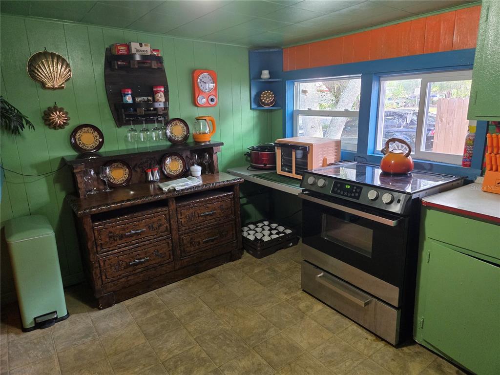 A kitchen features green paneled walls, a wooden hutch, and a black electric range — 1407 ILLINOIS AVENUE, ST CLOUD, FL