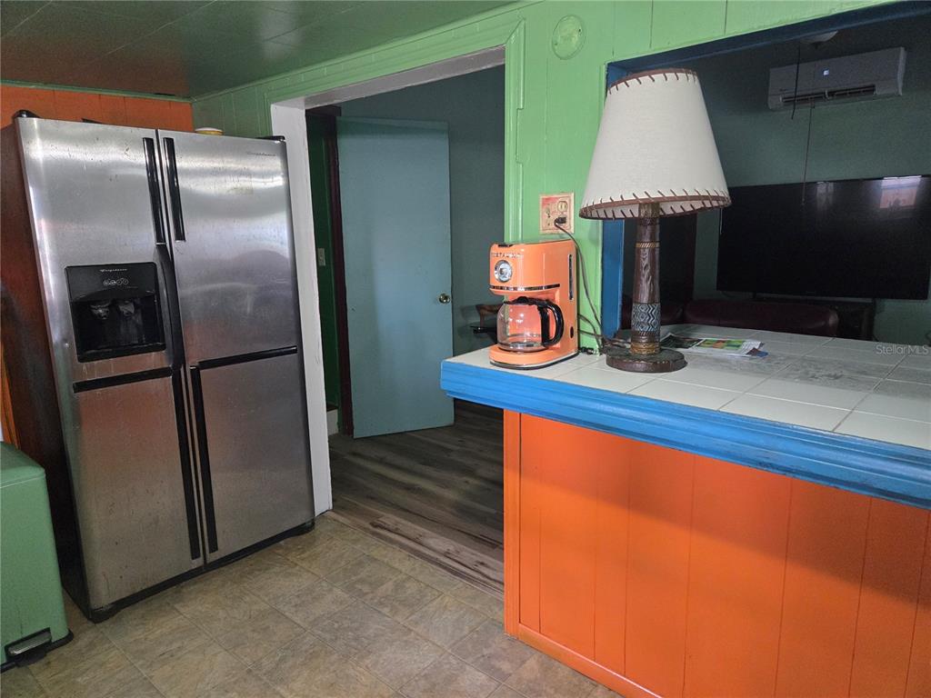 A kitchen features a stainless steel refrigerator, an orange counter, and a green wall — 1407 ILLINOIS AVENUE, ST CLOUD, FL