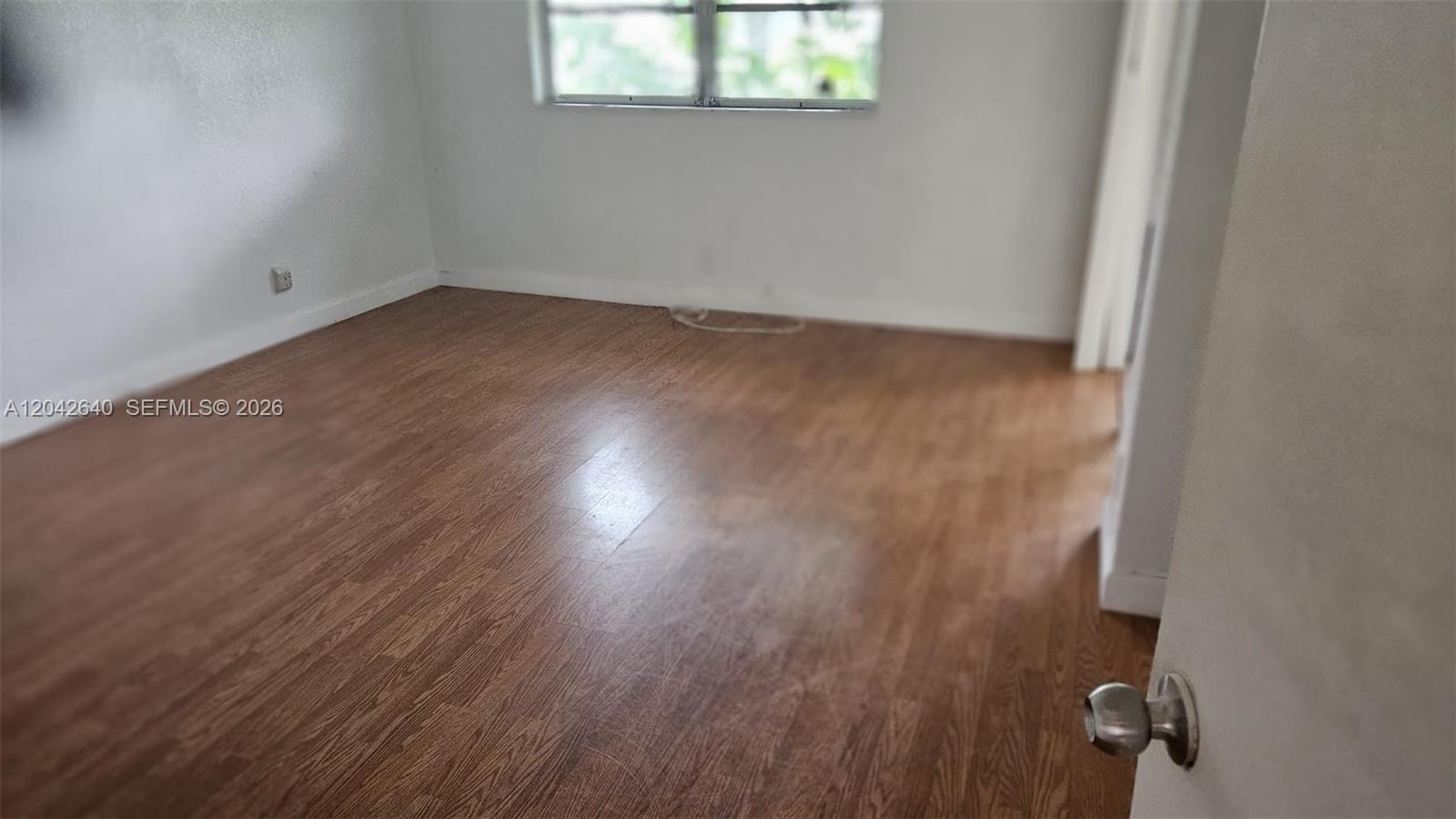 An empty room features wood-look flooring, white walls, and a single window — 8555 NW 10th St # B106, Plantation FL 33322, PLANTATION, FL