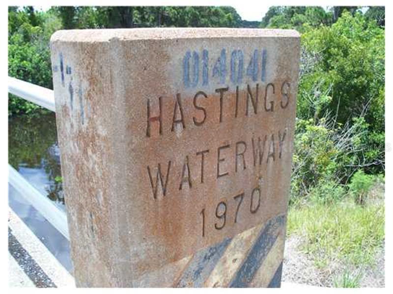 A concrete bridge marker displays the text Hastings Waterway 1970 next to a body of water — 2438 VANKEUREN DRIVE, PORT CHARLOTTE, FL