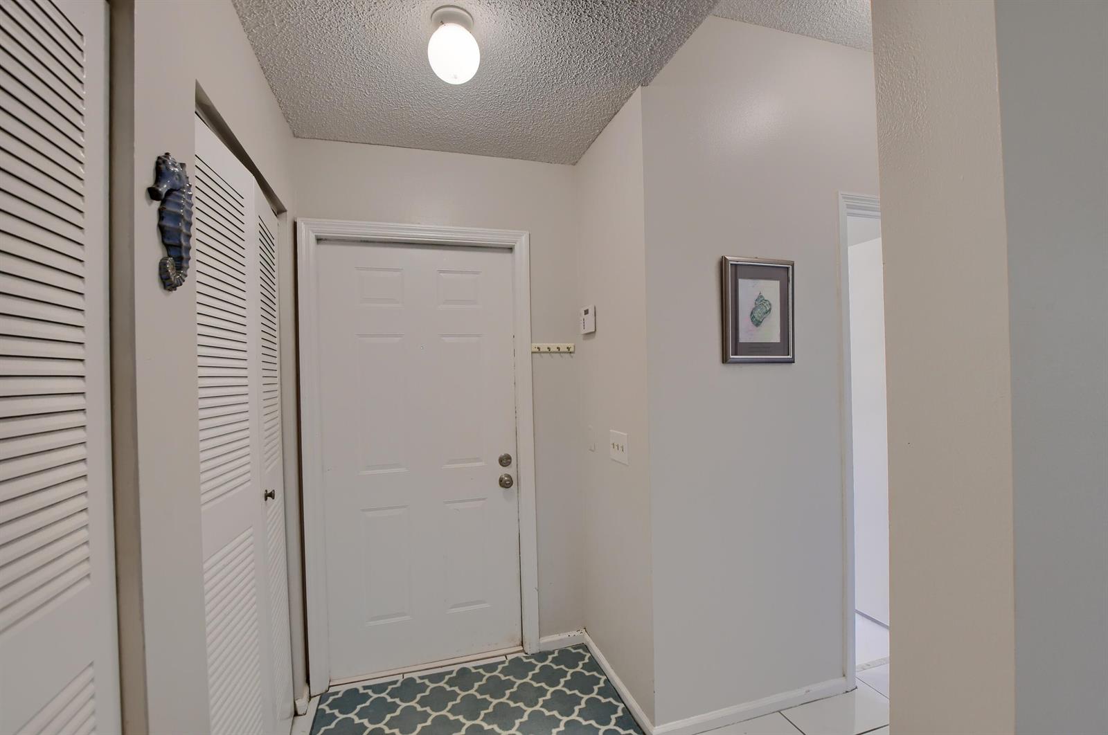 An entryway features a white door, a louvered closet, and patterned floor tiles — 6563 Via Regina, Boca Raton FL 33433, BOCA RATON, FL