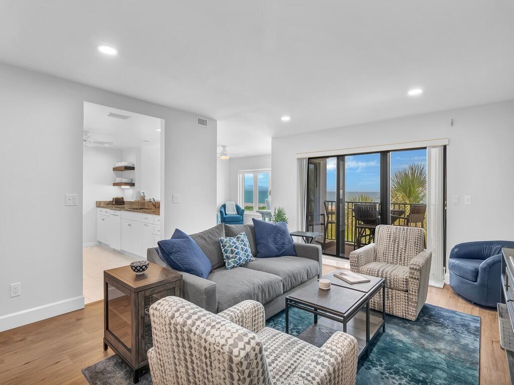 A living room with a gray sofa, patterned armchairs, and a view of the ocean — 1700 Ocean Drive # 306, Vero Beach FL 32963, VERO BEACH, FL