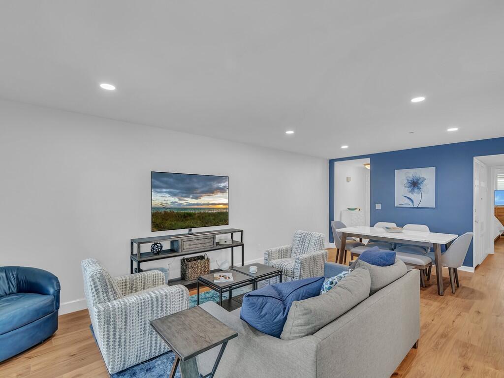 A living room with a grey sofa, patterned armchairs, a television, and a dining area — 1700 Ocean Drive # 306, Vero Beach FL 32963, VERO BEACH, FL