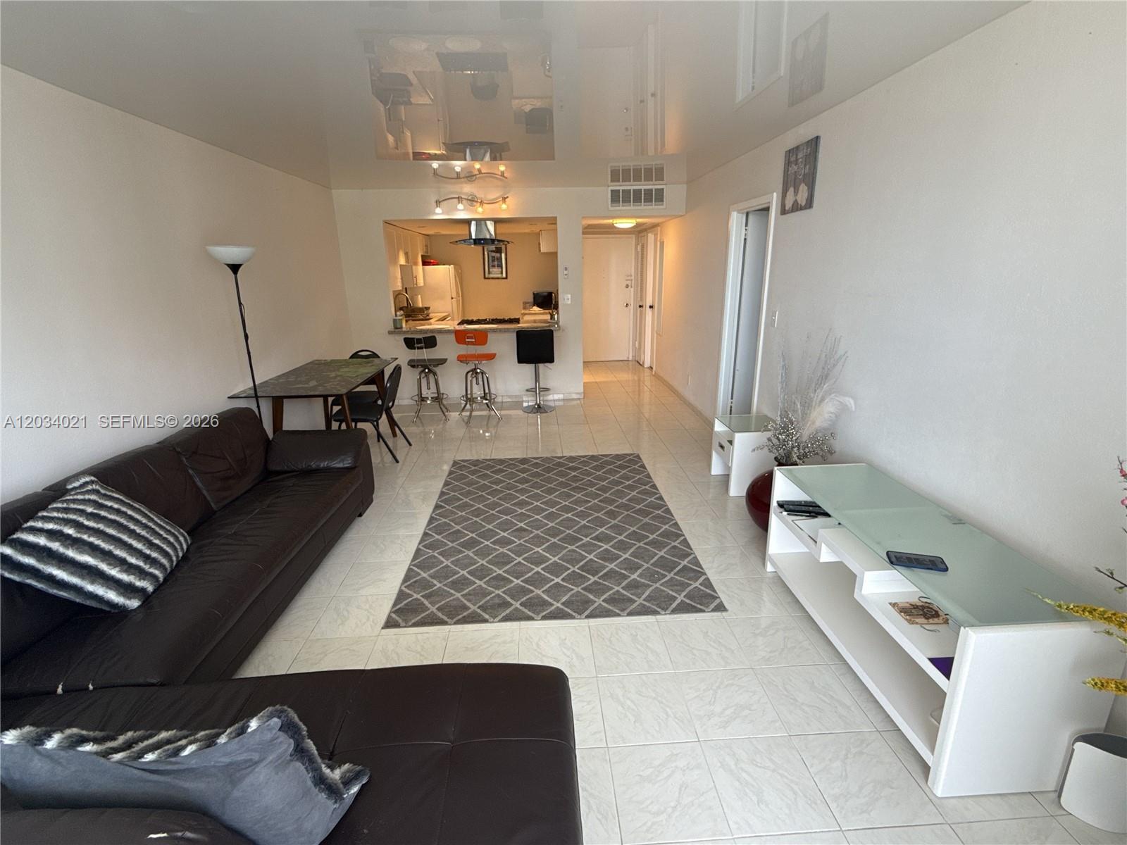 A living room features a dark leather sectional, a gray area rug, and a kitchen — 2030 S Ocean Dr # 1511, Hallandale Beach FL 33009, HALLANDALE BEACH, FL