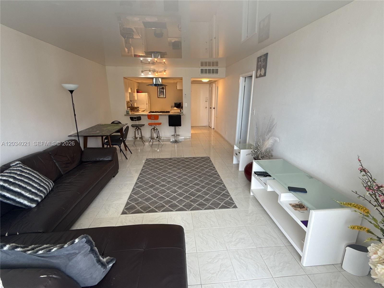 A living room with a dark leather sofa, tiled floors, and an open kitchen area — 2030 S Ocean Dr # 1511, Hallandale Beach FL 33009, HALLANDALE BEACH, FL
