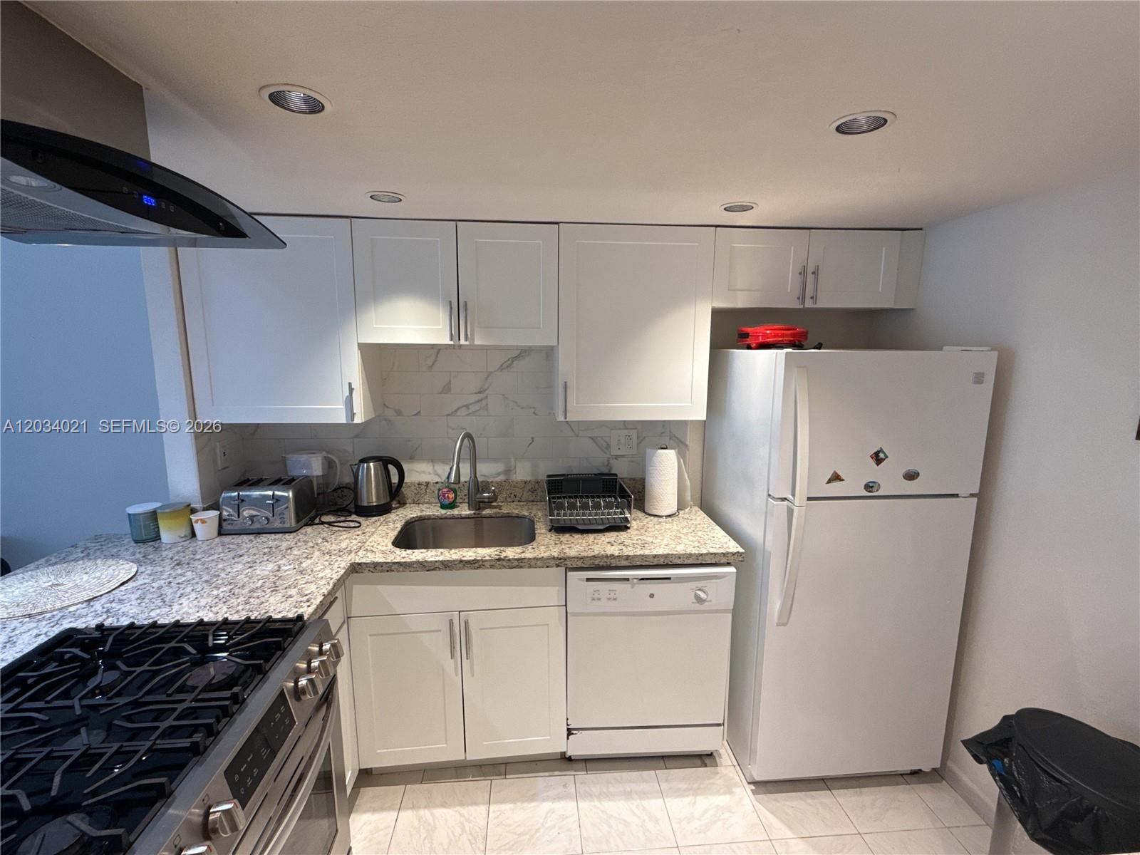 A kitchen features white cabinets, granite countertops, stainless steel appliances, and a tiled backsplash — 2030 S Ocean Dr # 1511, Hallandale Beach FL 33009, HALLANDALE BEACH, FL