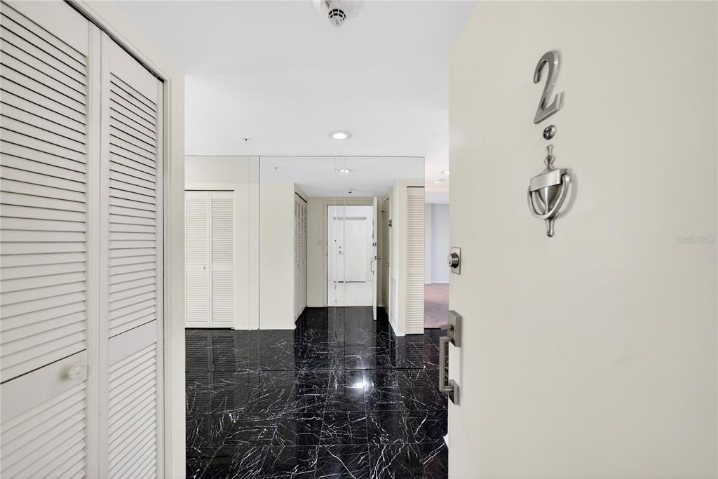 An entryway with black marble flooring, white louvered closet doors, and a mirrored wall — 770 S PALM AVENUE UNIT PH2, SARASOTA, FL