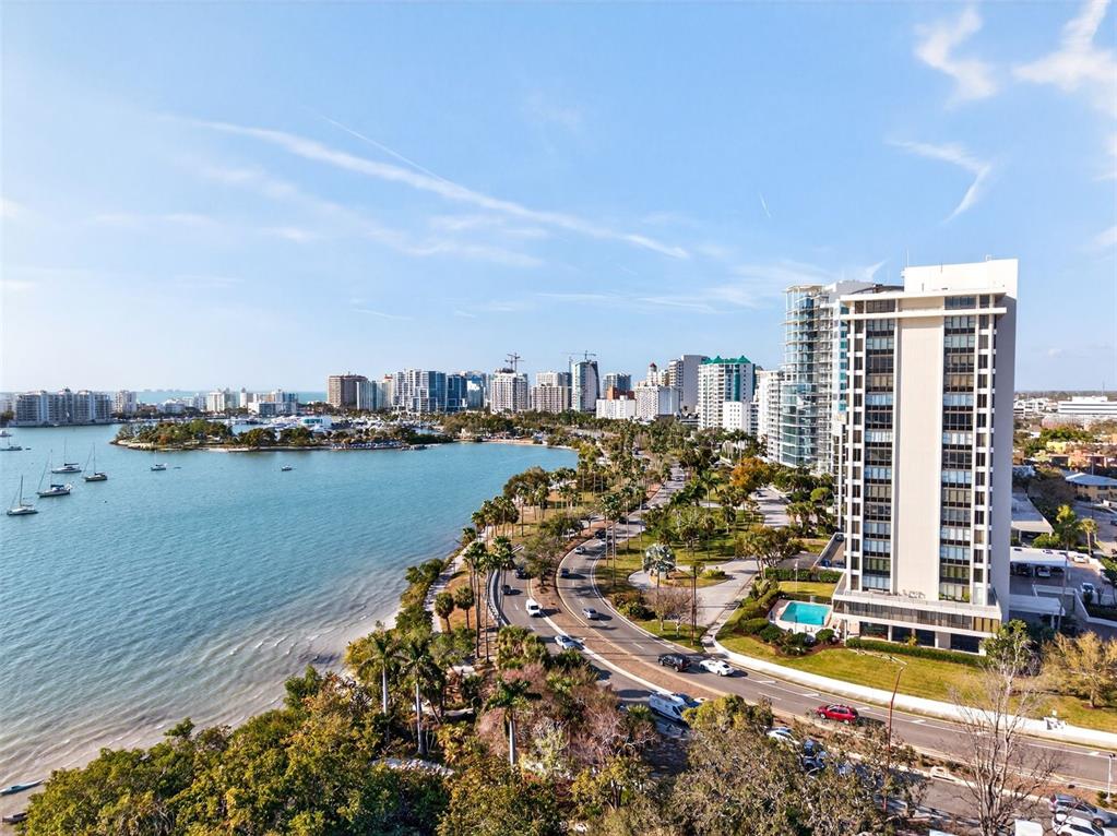 An aerial view shows a coastal road, palm trees, and high-rise buildings along the water — 770 S PALM AVENUE UNIT PH2, SARASOTA, FL