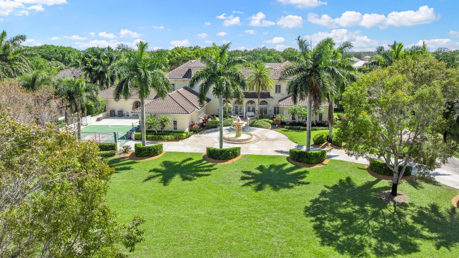 An aerial view of a large house with a circular driveway, fountain, and basketball court — 14535 Draft Horse Lane, Wellington FL 33414, WELLINGTON, FL