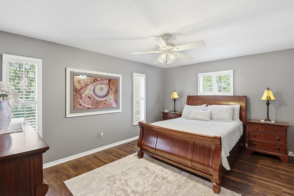 A bedroom features a wooden sleigh bed, gray walls, dark wood flooring, and a ceiling fan — 4601 S GATOR LOOP, HOMOSASSA, FL