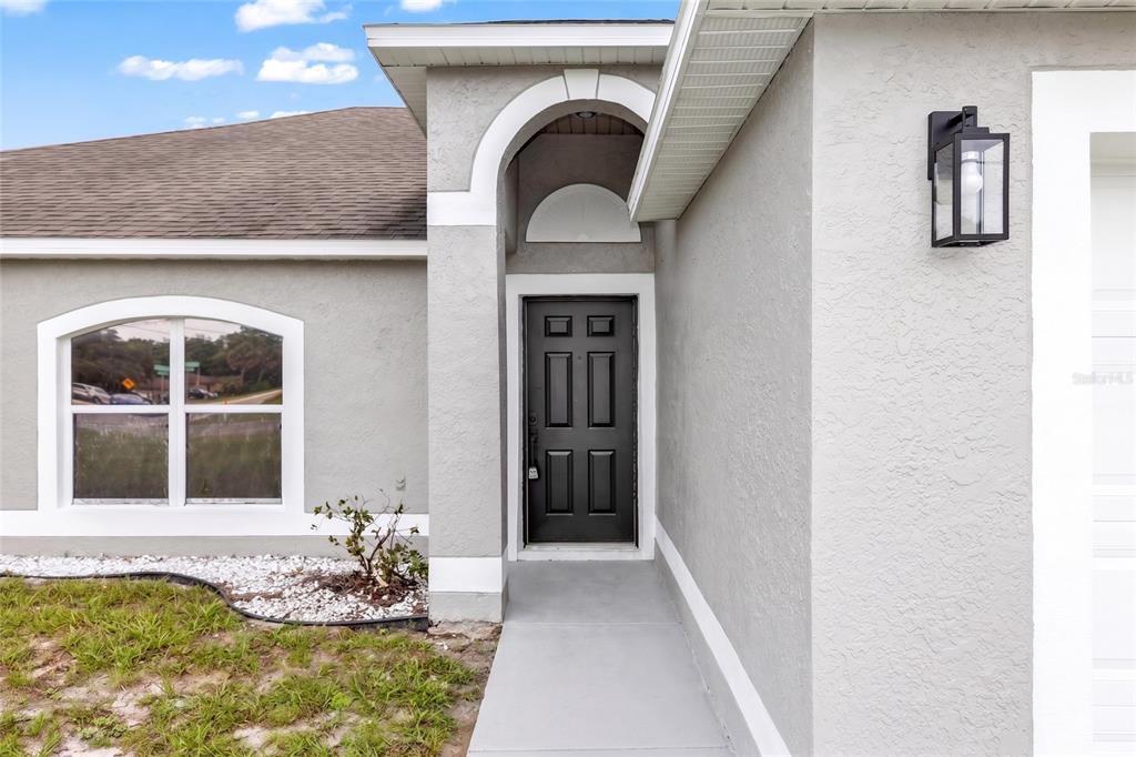 The exterior of a house features a black front door, a window, and a light — 2190 GLENLOCK DRIVE, DELTONA, FL