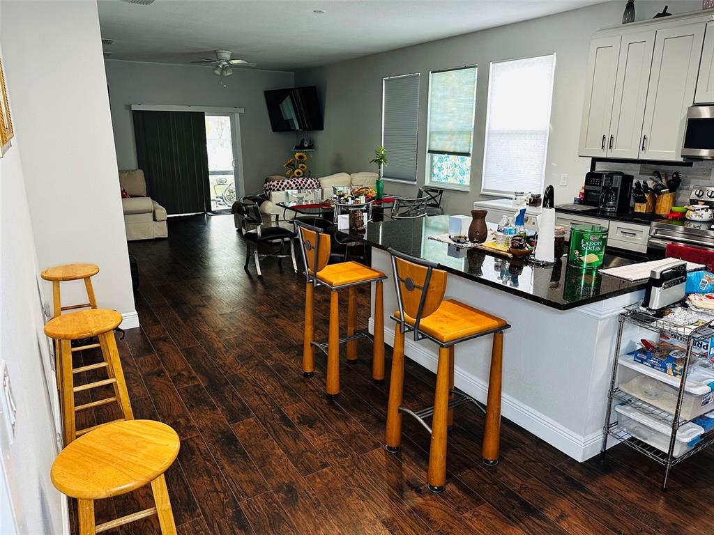 A kitchen with a dark granite island and bar stools opens into a living area — 606 W VOORHIS AVENUE, DELAND, FL