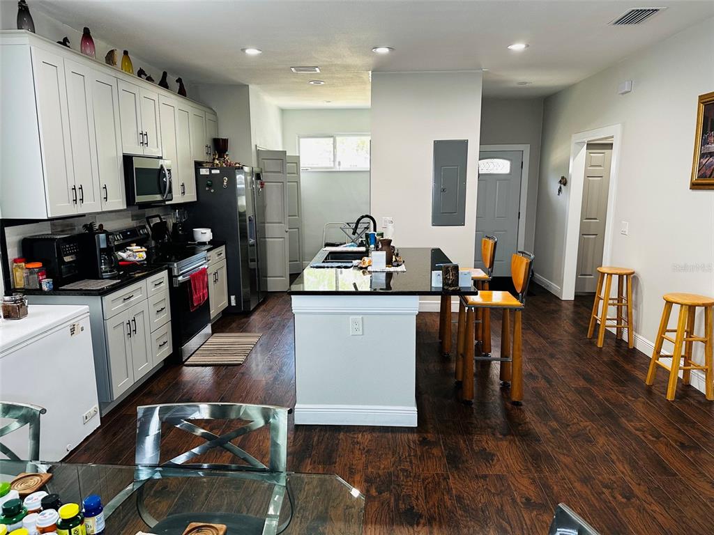 A kitchen features white cabinets, a black island with bar seating, and dark wood flooring — 606 W VOORHIS AVENUE, DELAND, FL