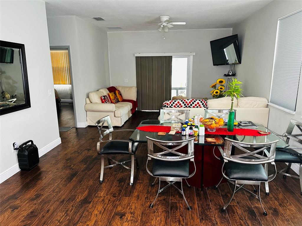 A dining area with a glass table and metal chairs sits in front of a living room — 606 W VOORHIS AVENUE, DELAND, FL