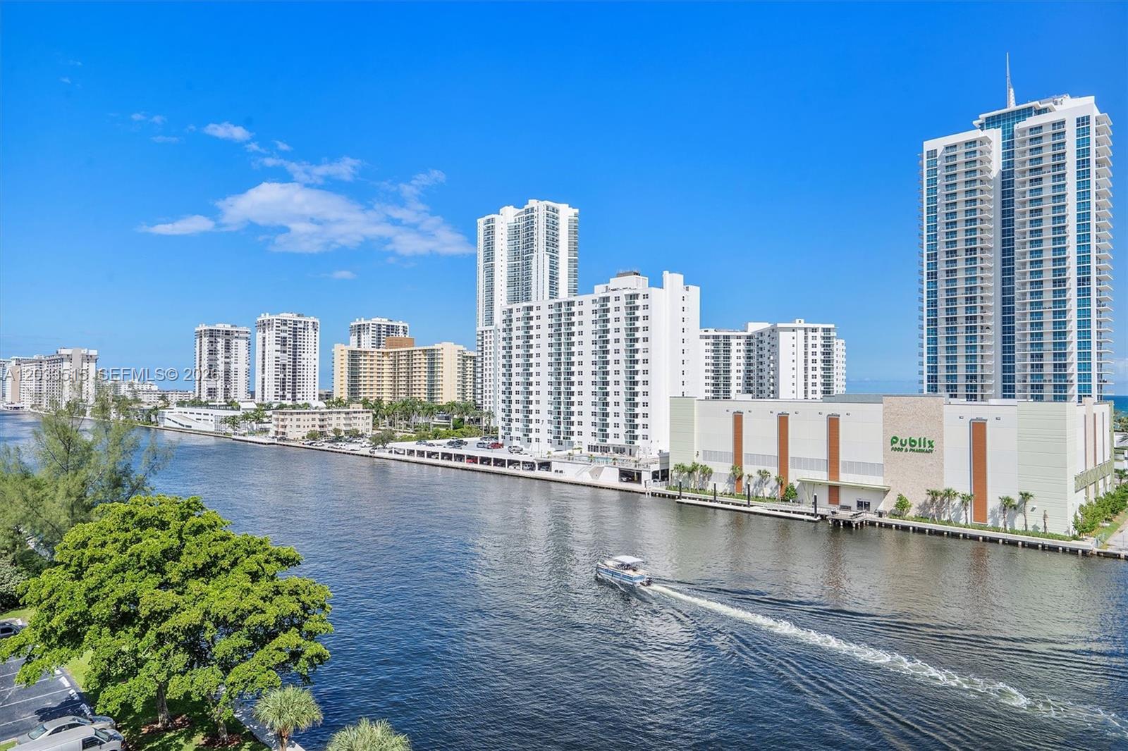 A boat travels along a waterway lined with high-rise buildings and a Publix supermarket — 600 Parkview Dr # 815, Hallandale Beach FL 33009, HALLANDALE BEACH, FL