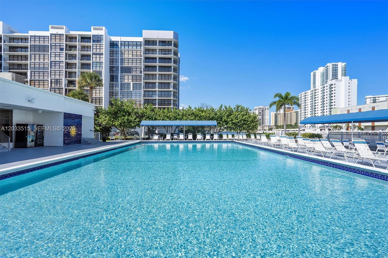A large rectangular swimming pool is surrounded by lounge chairs and tall residential buildings — 600 Parkview Dr # 815, Hallandale Beach FL 33009, HALLANDALE BEACH, FL