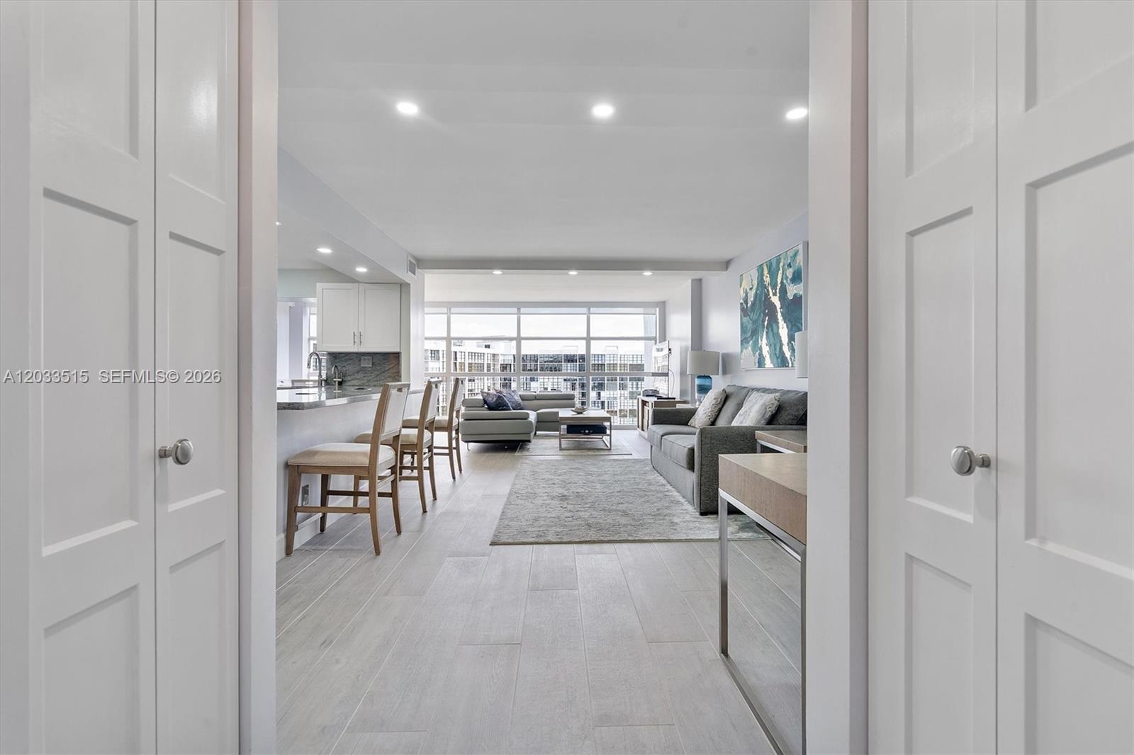 A bright, open-concept living area features light wood-look tile flooring and a modern kitchen — 600 Parkview Dr # 815, Hallandale Beach FL 33009, HALLANDALE BEACH, FL