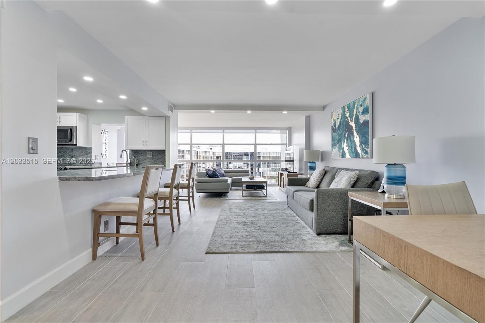 An open-concept living area features a kitchen with bar seating and a gray sofa — 600 Parkview Dr # 815, Hallandale Beach FL 33009, HALLANDALE BEACH, FL