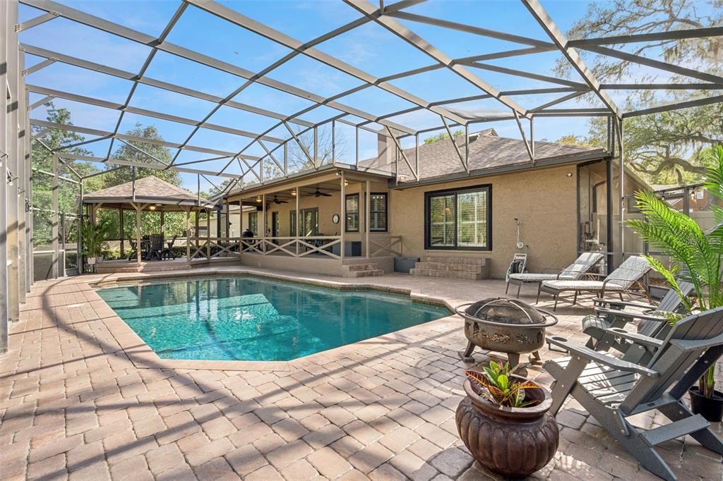 A screened-in patio features a swimming pool, a gazebo, and a paved deck area — 441 WILD OAK CIRCLE, LONGWOOD, FL