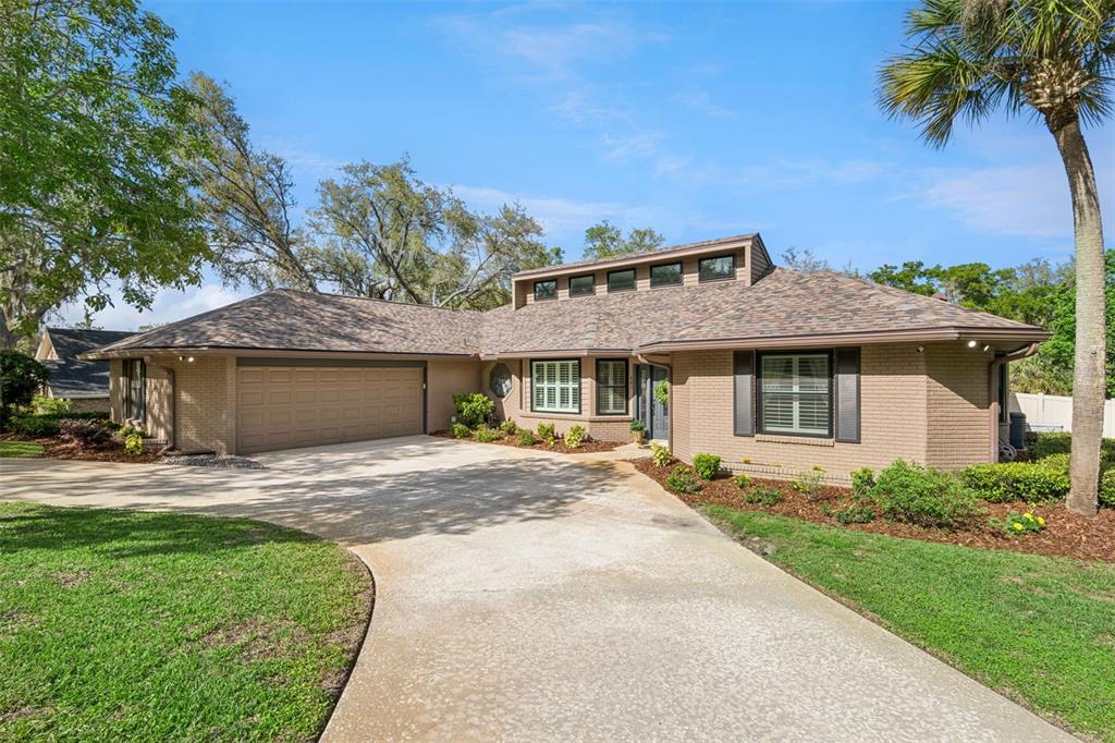 A single-story brick house with a multi-car garage, a concrete driveway, and a palm tree — 441 WILD OAK CIRCLE, LONGWOOD, FL