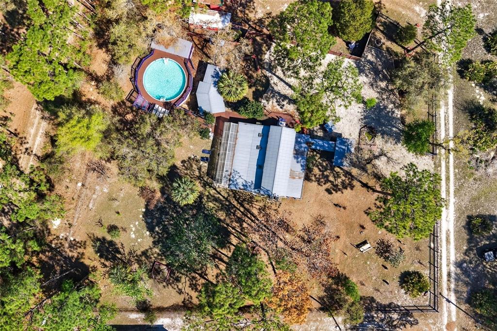 An elevated wooden deck surrounds an above-ground swimming pool with a covered seating area — 5080 N ALEXA TERRACE, CRYSTAL RIVER, FL