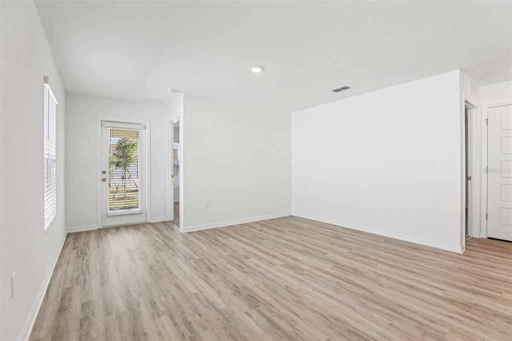 An empty room with light wood-look flooring, white walls, a glass door, and recessed lighting — 5377 WILLOW CREEK, HAINES CITY, FL