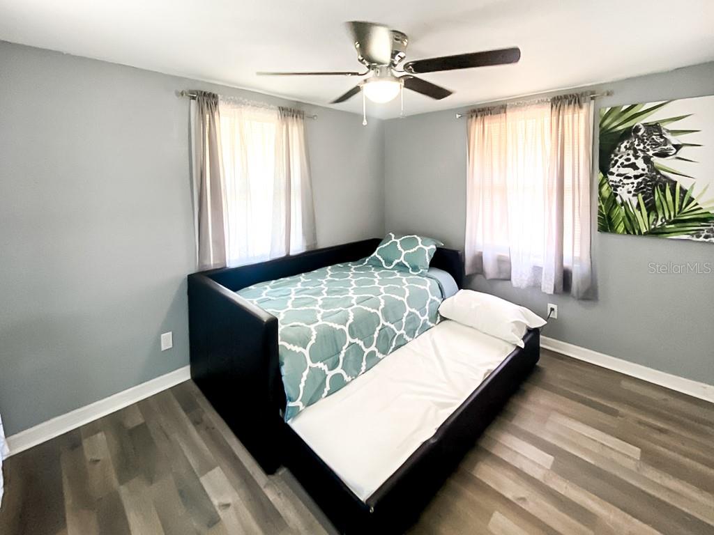 A bedroom features a black daybed with a trundle, light gray walls, and wood flooring — 4303 CHESTNUT AVENUE, SARASOTA, FL