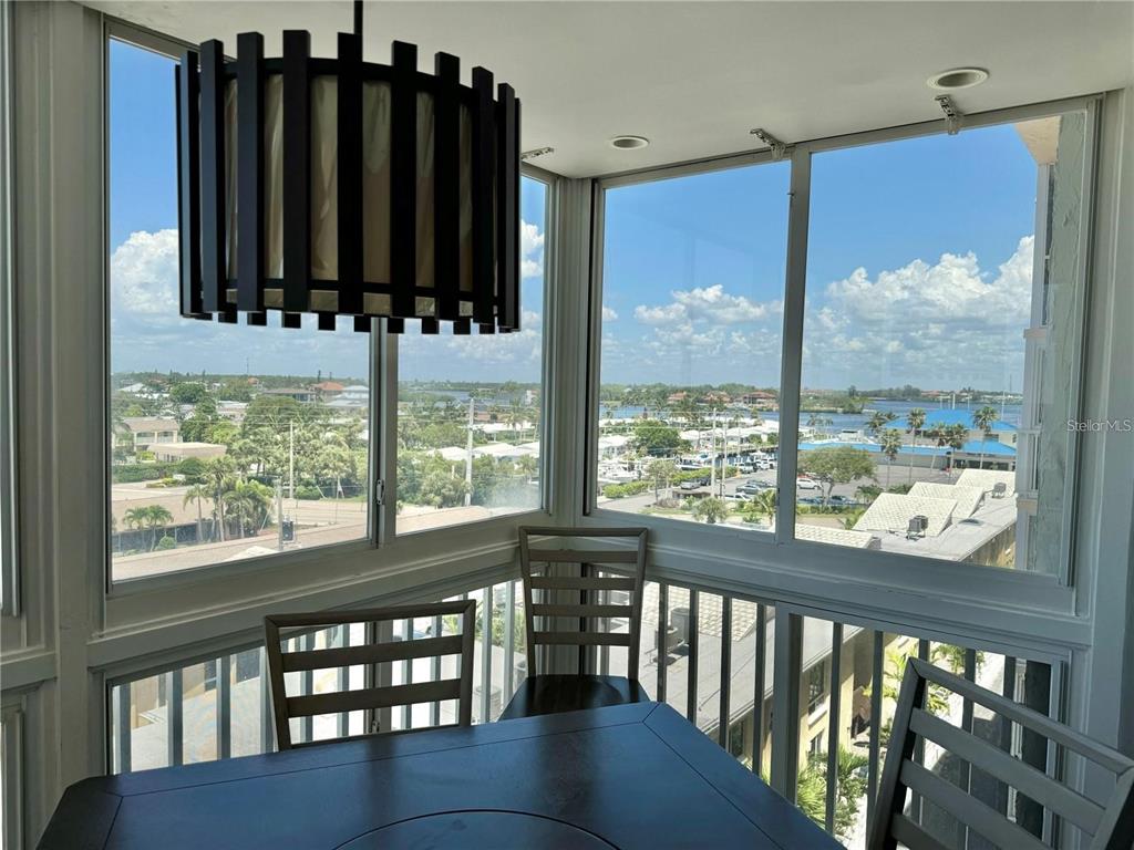 A dining area with a dark wood table and chairs overlooks a coastal water view — 1255 TARPON CENTER DRIVE UNIT 612, VENICE, FL