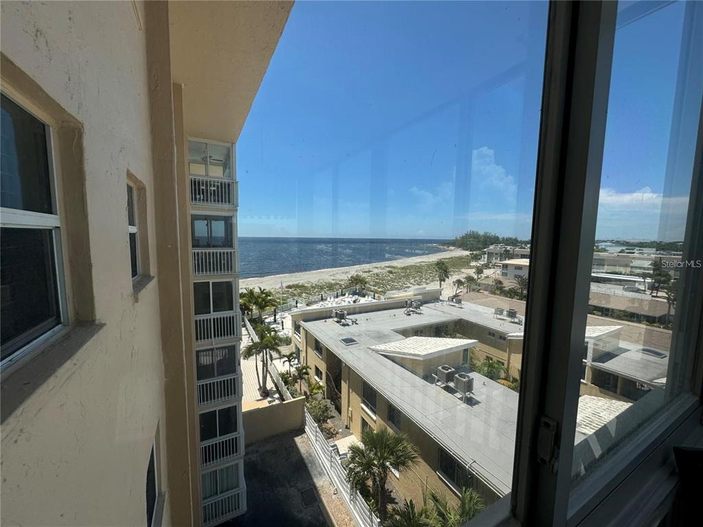 A high-angle view from a window overlooking a beach, ocean, and adjacent buildings — 1255 TARPON CENTER DRIVE UNIT 612, VENICE, FL