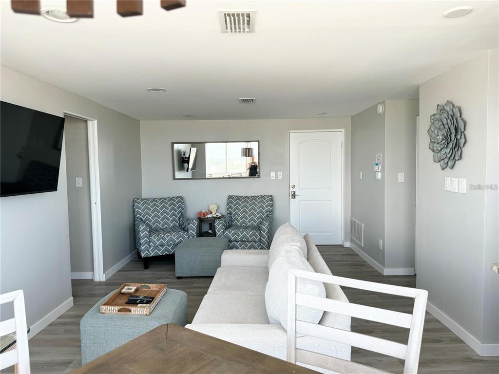 A living room features a white sofa, two patterned armchairs, and light wood-look flooring — 1255 TARPON CENTER DRIVE UNIT 612, VENICE, FL