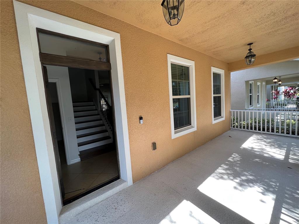 A covered porch with a doorway leading to an interior staircase and two windows — 6526 GOLDEN DEWDROP TRAIL, WINDERMERE, FL