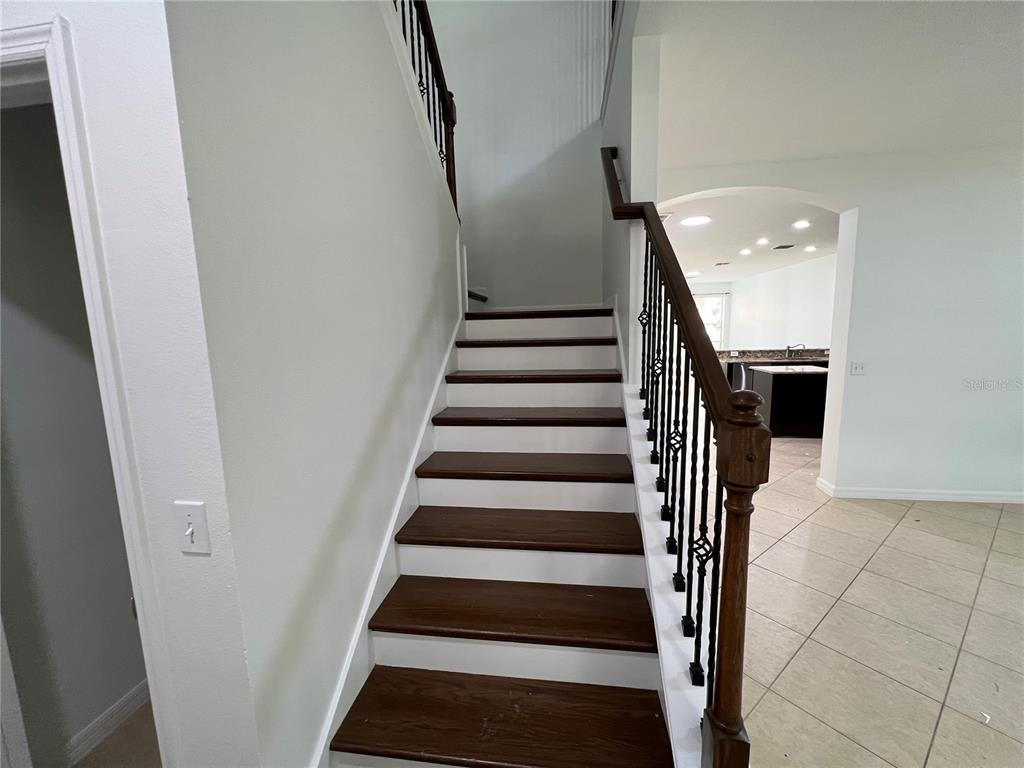 A staircase with dark wood treads and white risers features a dark metal railing — 6526 GOLDEN DEWDROP TRAIL, WINDERMERE, FL