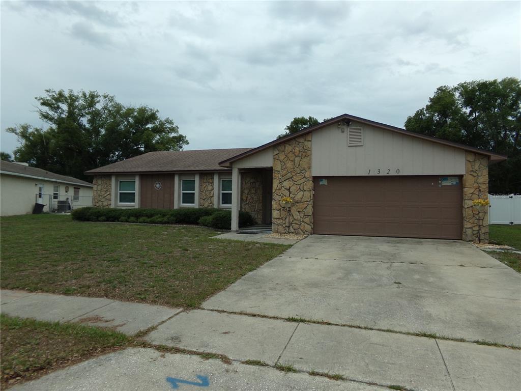 A single-story house with a stone facade, brown siding, and an attached two-car garage — 1320 GLADIOLAS DR, WINTER PARK, FL