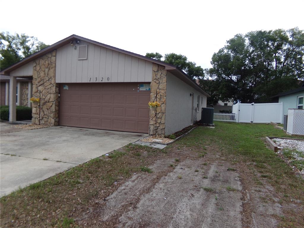 A single-story house exterior features a brown garage door, stone accents, and a side yard — 1320 GLADIOLAS DR, WINTER PARK, FL