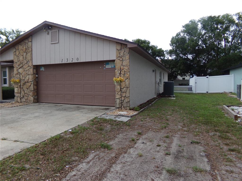 A single-story house with a brown garage door, stone accents, and a side yard — 1320 GLADIOLAS DR, WINTER PARK, FL