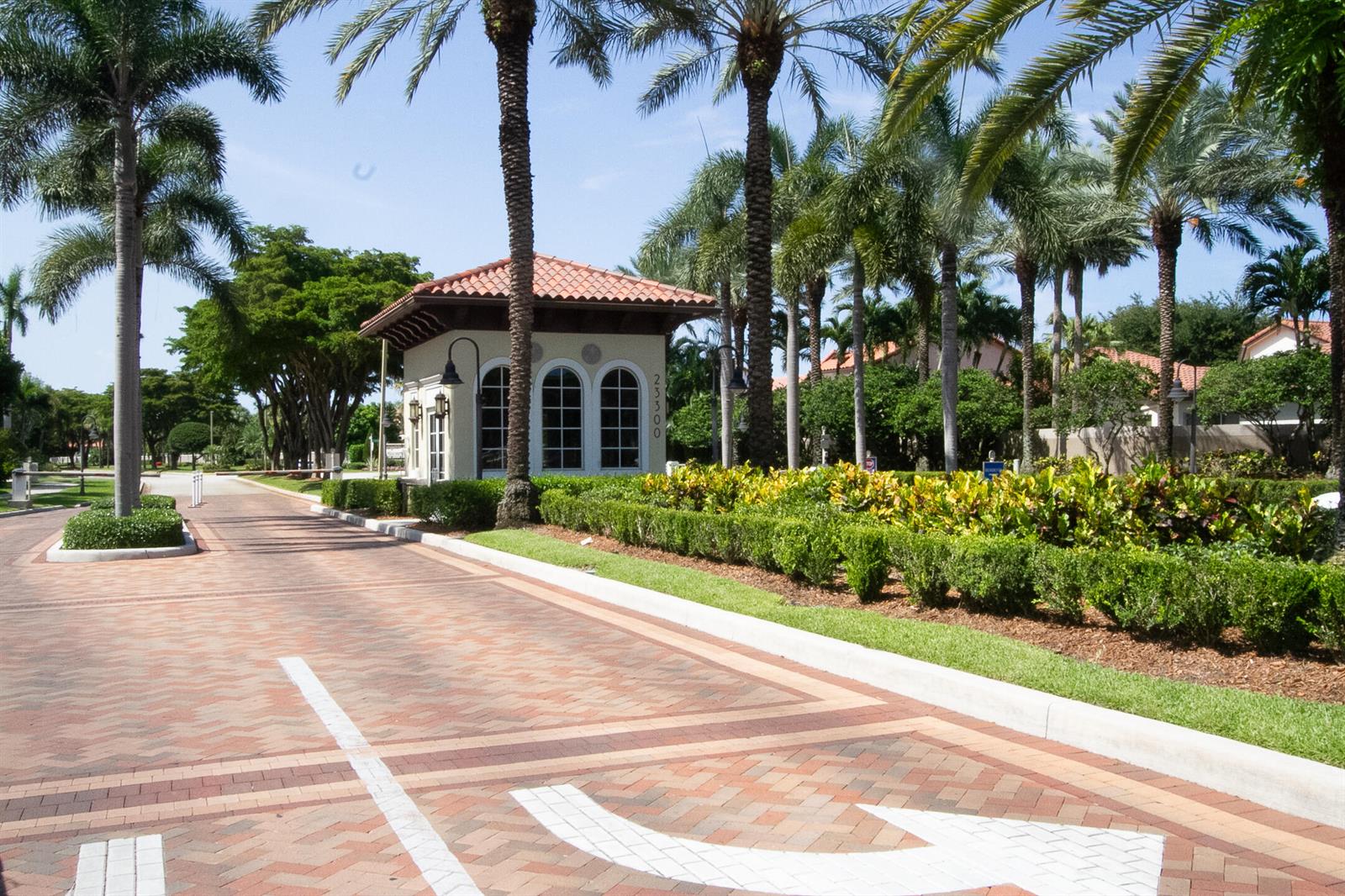 A gated community entrance features a small guardhouse with a tiled roof and palm trees — 23045 Clear Echo Drive # 76, Boca Raton FL 33433, BOCA RATON, FL