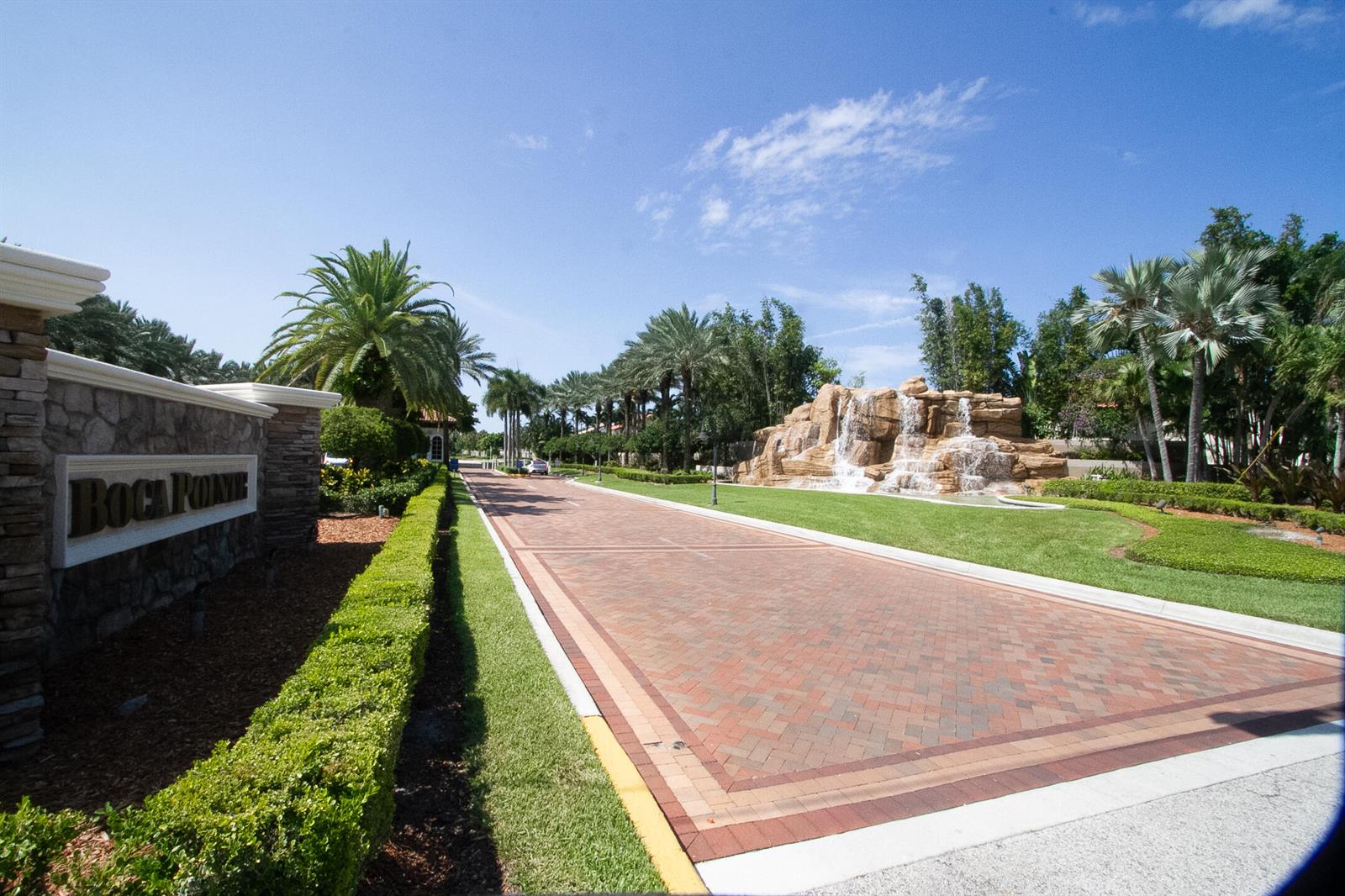 A brick driveway leads past a stone sign and a large waterfall feature at Boca Pointe — 23045 Clear Echo Drive # 76, Boca Raton FL 33433, BOCA RATON, FL