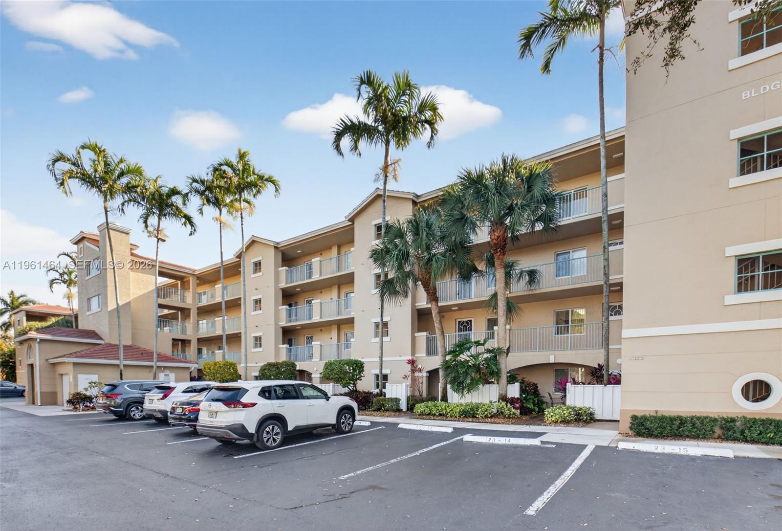 A multi-story apartment building with palm trees and parked cars in the foreground — 12540 Majesty Cir # 208, Boynton Beach FL 33437, BOYNTON BEACH, FL
