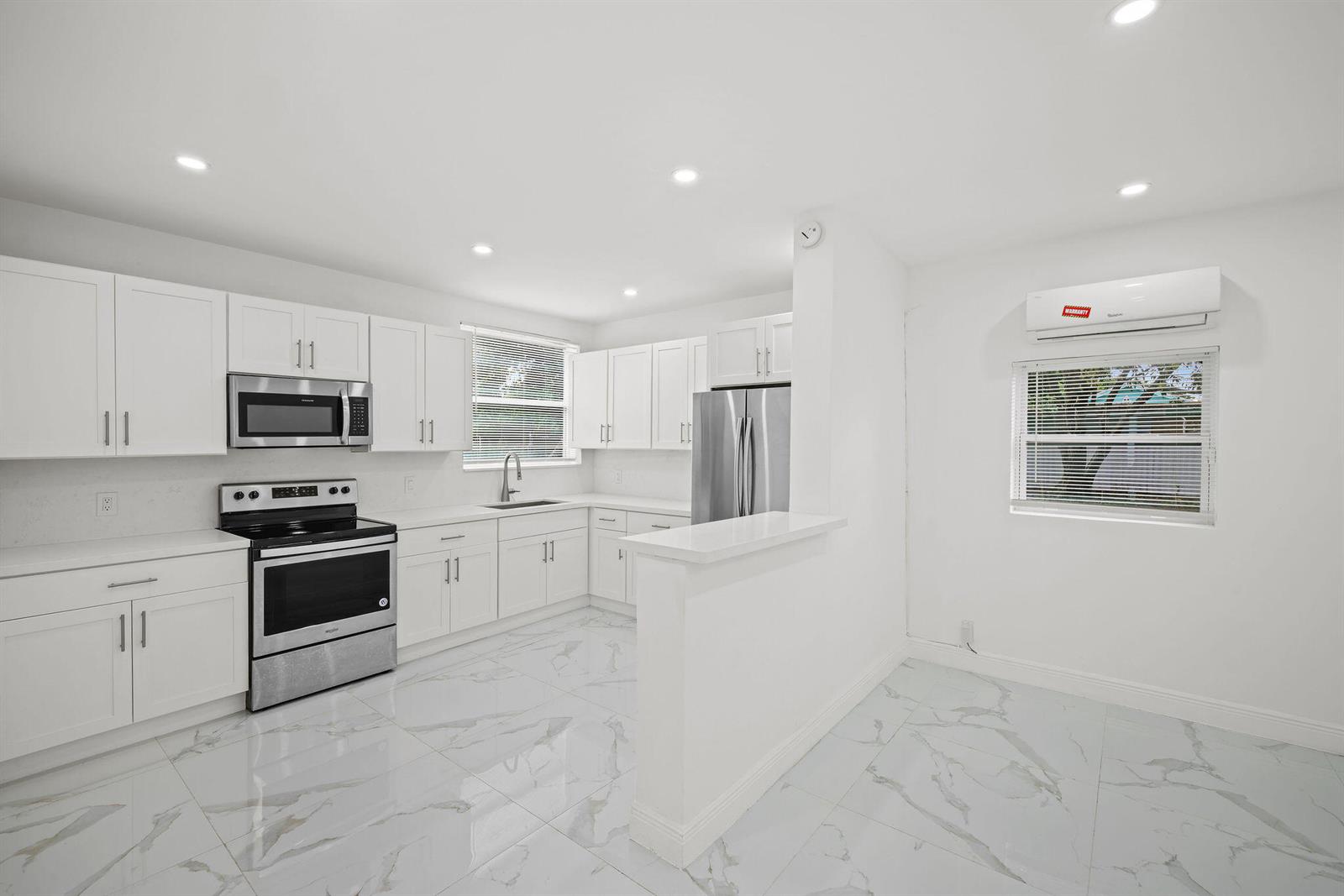 A modern kitchen features white cabinets, stainless steel appliances, and white marble-patterned tile flooring — 332 NW 97th Street, Miami FL 33150, MIAMI, FL