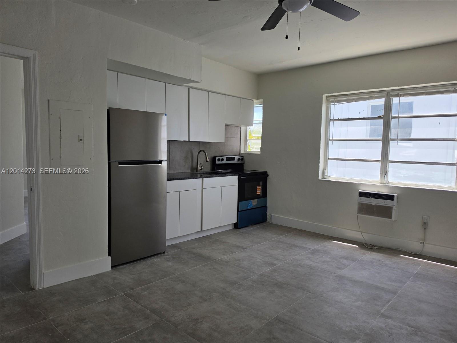 A kitchen features white cabinets, stainless steel appliances, and gray tile flooring — 1965 Calais Dr # 7, Miami Beach FL 33141, MIAMI BEACH, FL