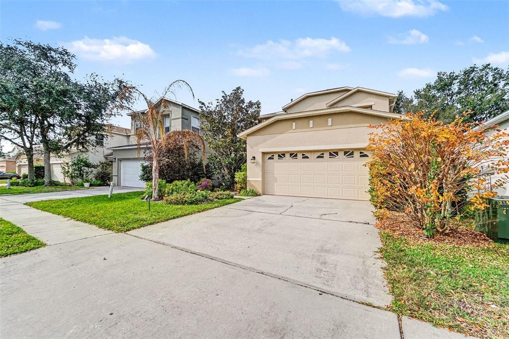A two-story suburban house with a beige stucco exterior, a two-car garage, and a driveway — 2449 SILVERMOSS DRIVE, WESLEY CHAPEL, FL