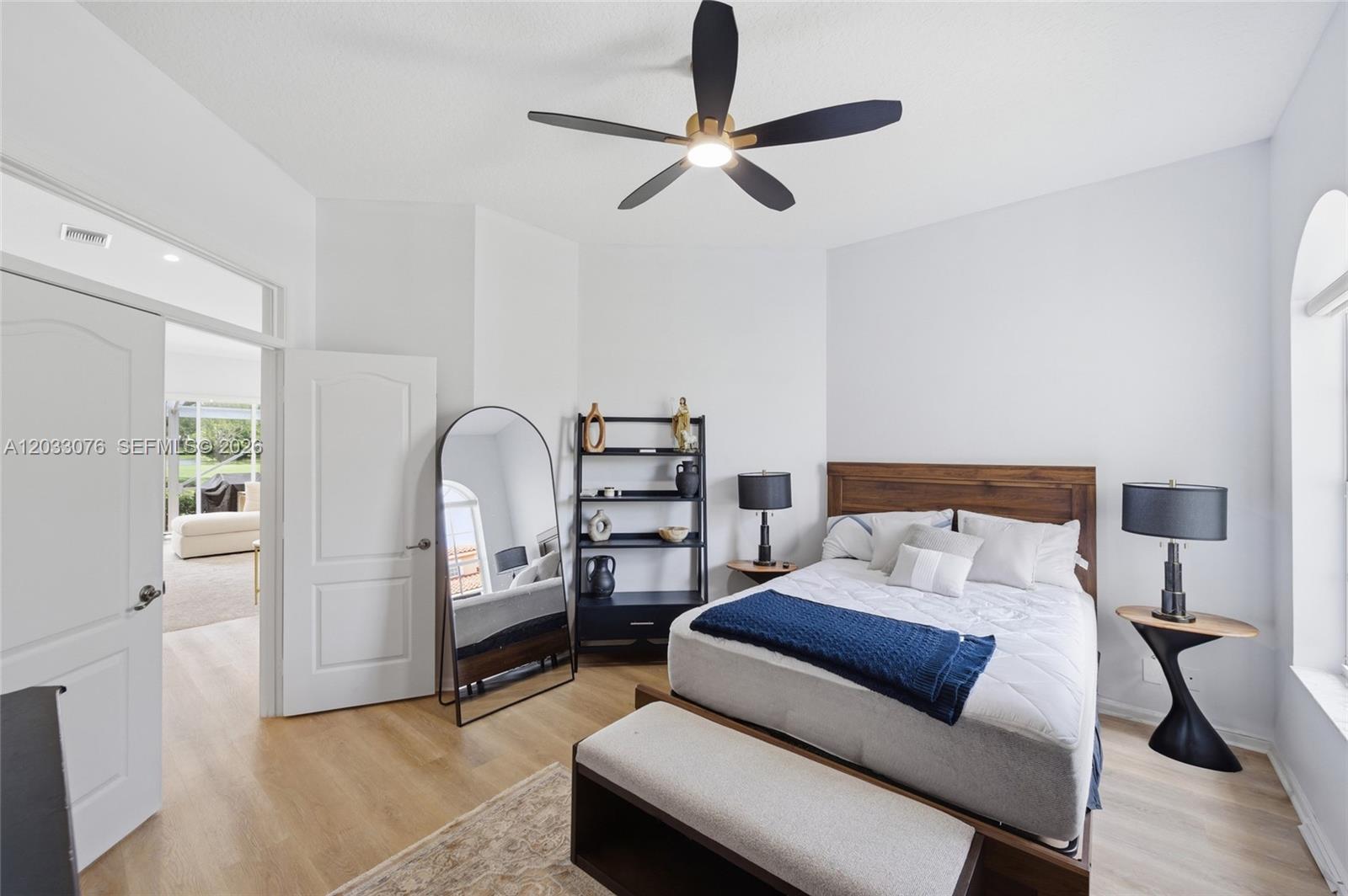 A bedroom features a wooden bed frame, a floor mirror, and a black ceiling fan — 8141 Sandpiper Way, West Palm Beach FL 33412, WEST PALM BEACH, FL