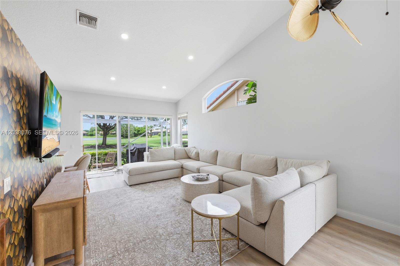 A living room features a large sectional sofa, patterned wallpaper, and a vaulted ceiling — 8141 Sandpiper Way, West Palm Beach FL 33412, WEST PALM BEACH, FL