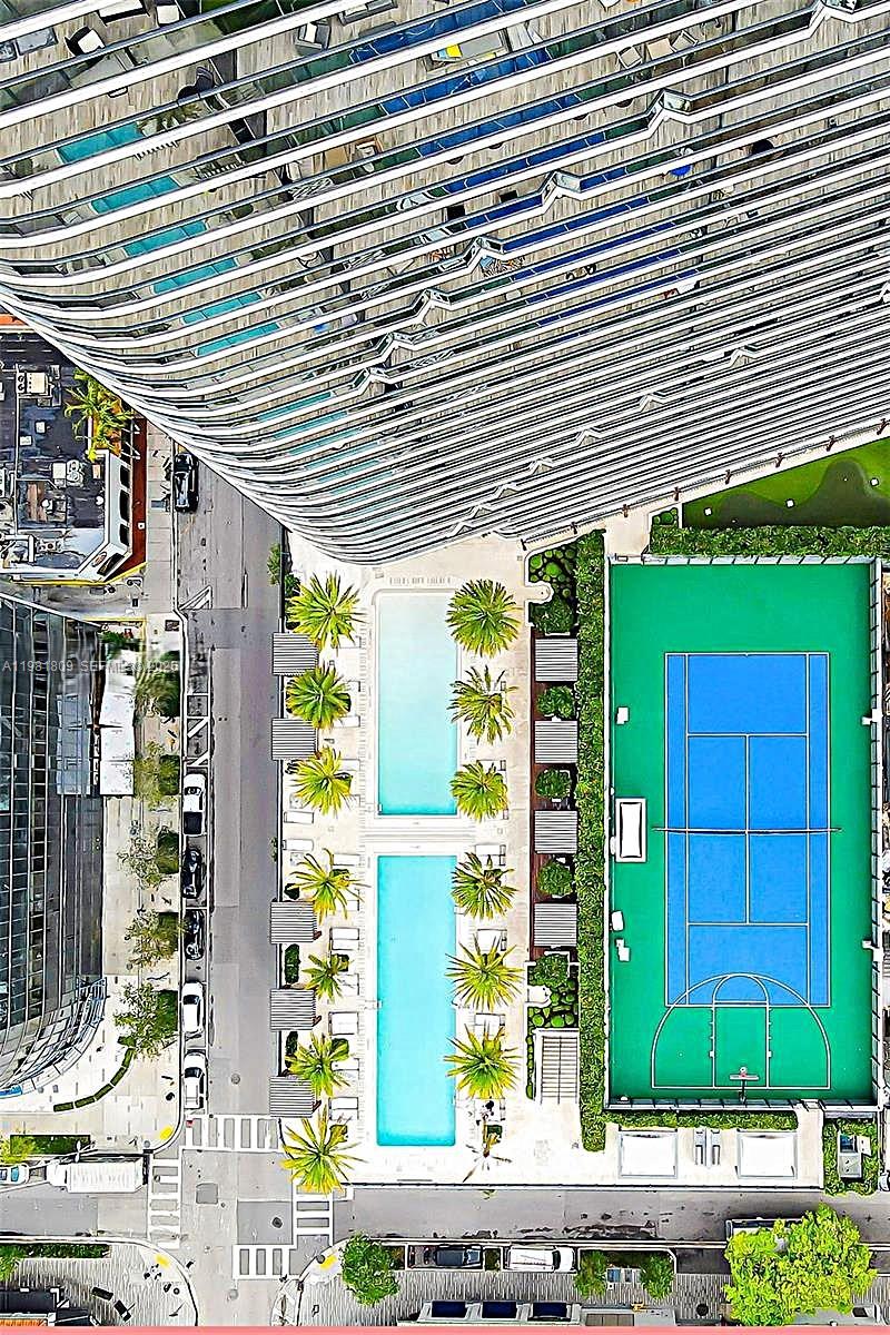An aerial view shows a high-rise building with two swimming pools and a basketball court — 801 S Miami Ave # 1203, Miami FL 33130, MIAMI, FL