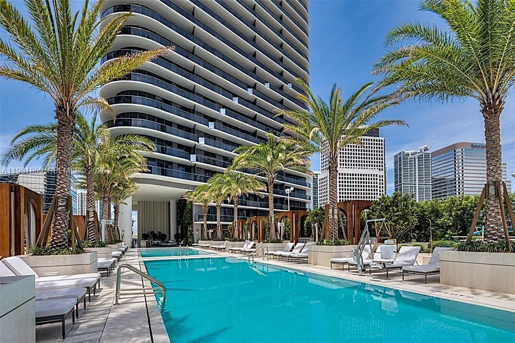 A swimming pool sits on a terrace in front of a modern high-rise building — 801 S Miami Ave # 1203, Miami FL 33130, MIAMI, FL