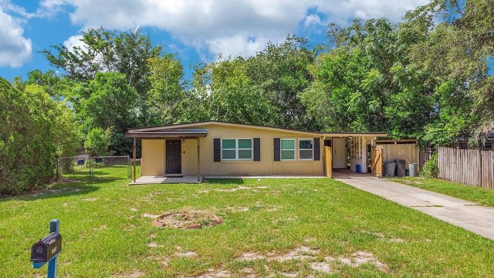 A single-story house with a tan exterior, a front porch, and a concrete driveway — 310 E 6TH STREET, CHULUOTA, FL