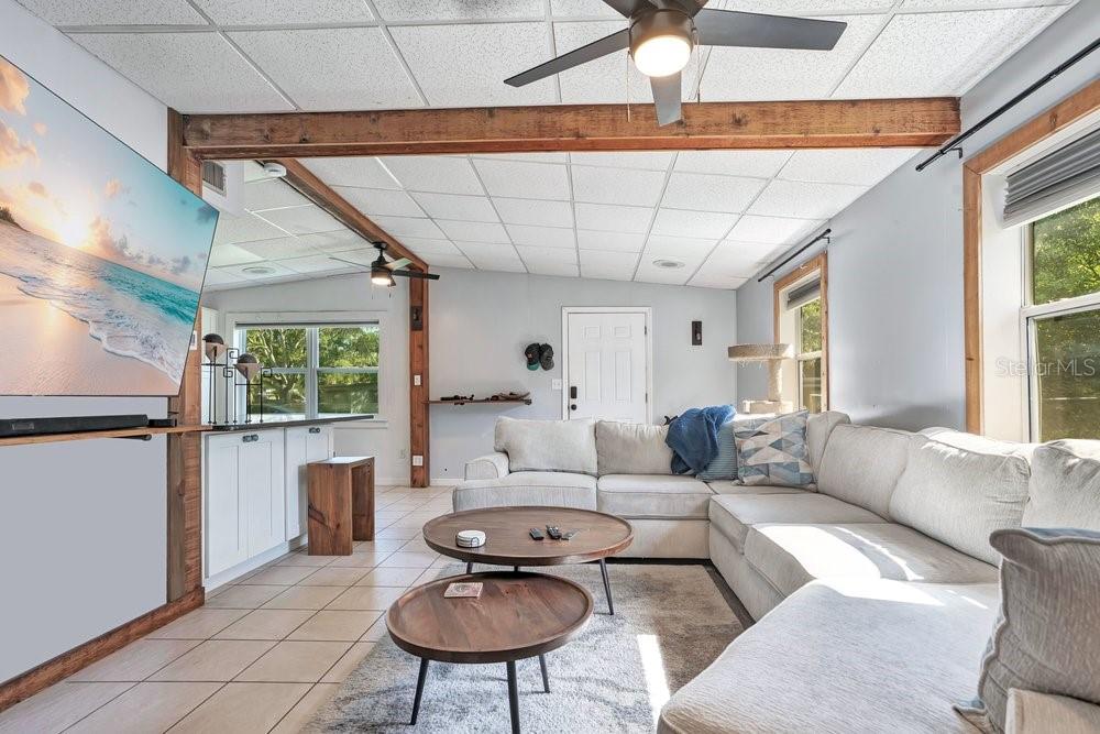 A living room features a sectional sofa, two round coffee tables, and exposed wooden beams — 310 E 6TH STREET, CHULUOTA, FL